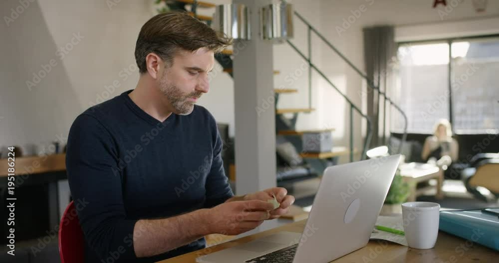 Handsome Man at Home sitting at Table throwing away Note on sticky memo Handsome Man at Home sitting at Table throwing away Note on sticky memo