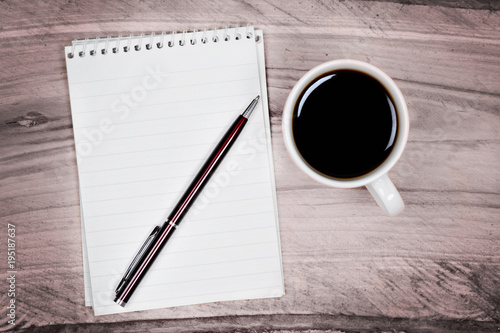 Blank notepad with pen and coffee cup on table