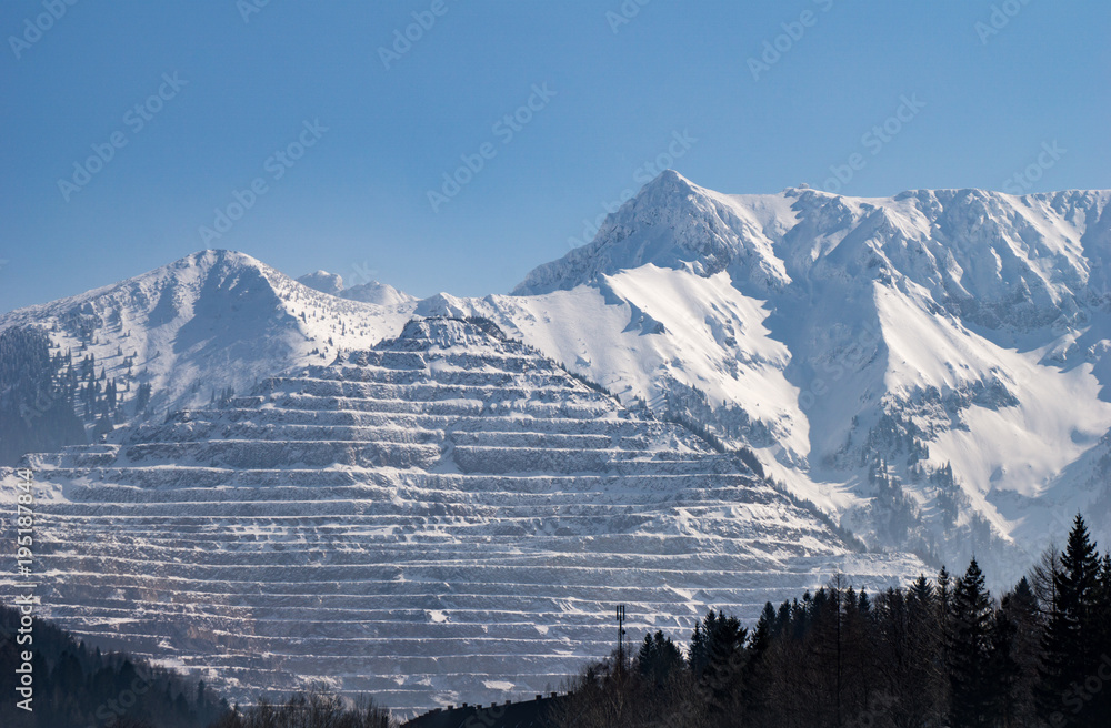 The Erzberg surface mine in winter with majestic mountain range beside it