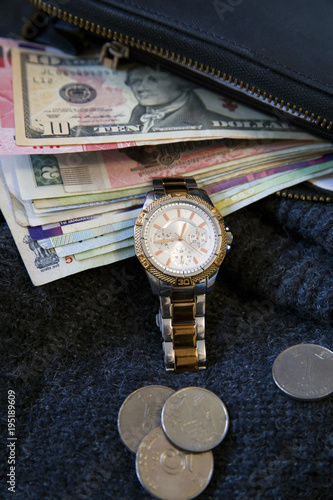 Women's watch, wallet and money cash and coin is on wool. Dollars, yuan, Hong Kong dollars, baht, Lira