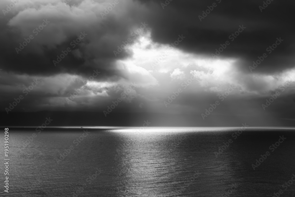 Single Boat in Beam of Light with Huge Sea and Clouds