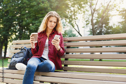 Beautiful woman sitting and using smartphone outdoors