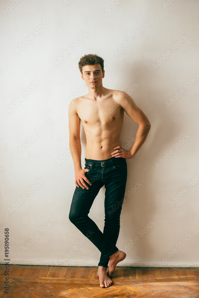 A young, handsome guy posing with a gnawed torso, demonstrating a sports body, muscles, relief, a pumped-up body. Background white wall. Shooting with natural light, minimal, natural retouching A young, handsome guy posing with a gnawed torso, demonstrating a sports body, muscles, relief, a pumped-up body. Background white wall. Shooting with natural light, minimal, natural retouching