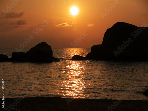 Sonnenuntergang am Meer zwischen zwei gro  en Felsen im Wasser