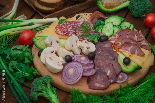 Cold smoked meat with prosciutto, salami, bacon, pork chops, cheese, mushrooms, cucumber, bread, avocado, onion and olives. Wooden rustic background. Top view