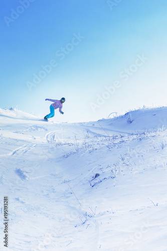 One snowboarder ride from a high snowy mountain under a blue sky.