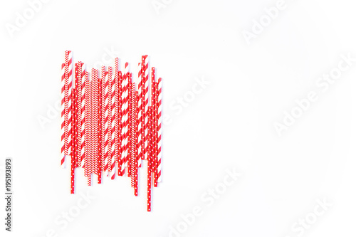 Fototapeta Naklejka Na Ścianę i Meble -  A stack of red and white striped and spotted straws for cocktails on a white background. Festive mood concept. Flat lay, top view, copyspace
