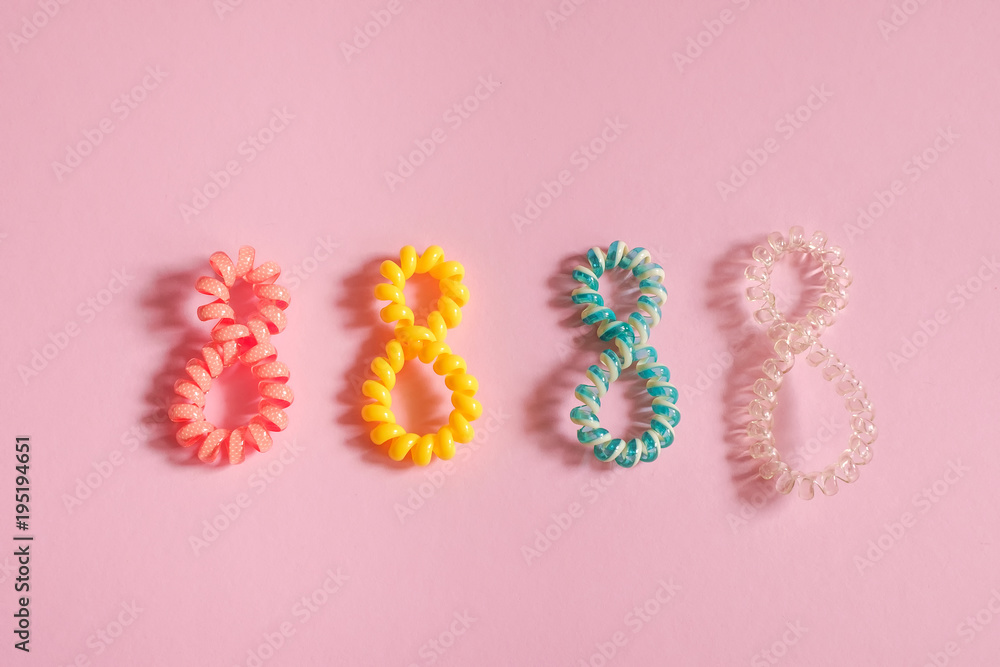 Colorful hair bands in the form of number 8 on pink background. Place for text, design, pattern.