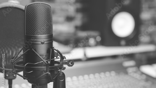 black and white condenser microphone on audio mixing board & studio monitor speakers background. recording concept photo