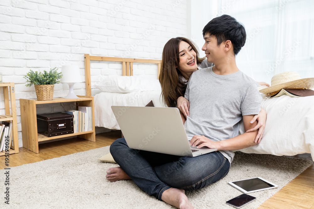 Young asian couple looking together using computer laptop internet shopping online or searching data honeymoon trip travel at bedroom in house.Happy lover hug each other and smiling on bed at home Young asian couple looking together using computer laptop internet shopping online or searching data honeymoon trip travel at bedroom in house.Happy lover hug each other and smiling on bed at home