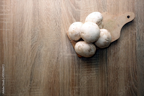 Fresh champignon mushrooms on rustic wooden table, space for a text