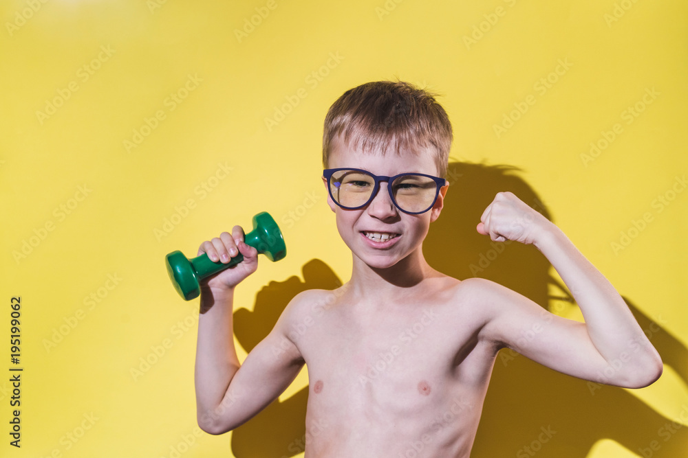 Smiling small boy in glasses holding dumbbell in hand. Funny sport concept.  Stock Photo | Adobe Stock