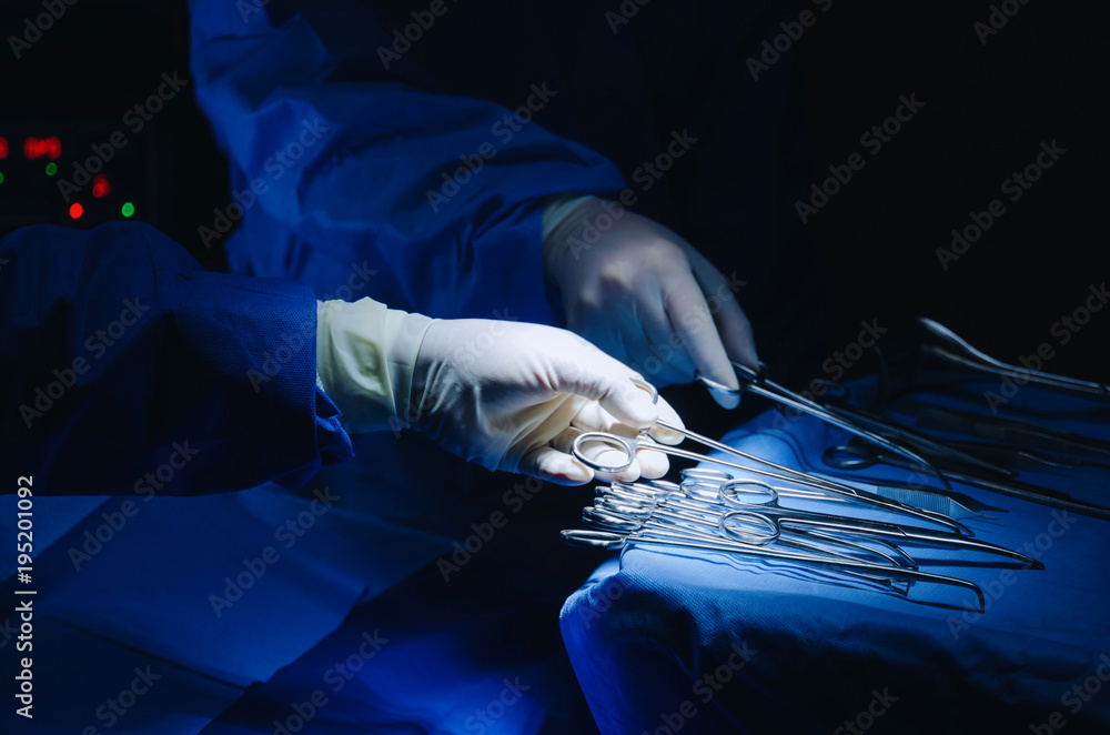 close up surgeons hand taking scissors, forceps and surgical instruments on  table for operation with colleagues performing work in operation room at  hospital, emergency case, surgery, medical concept Stock-foto | Adobe Stock