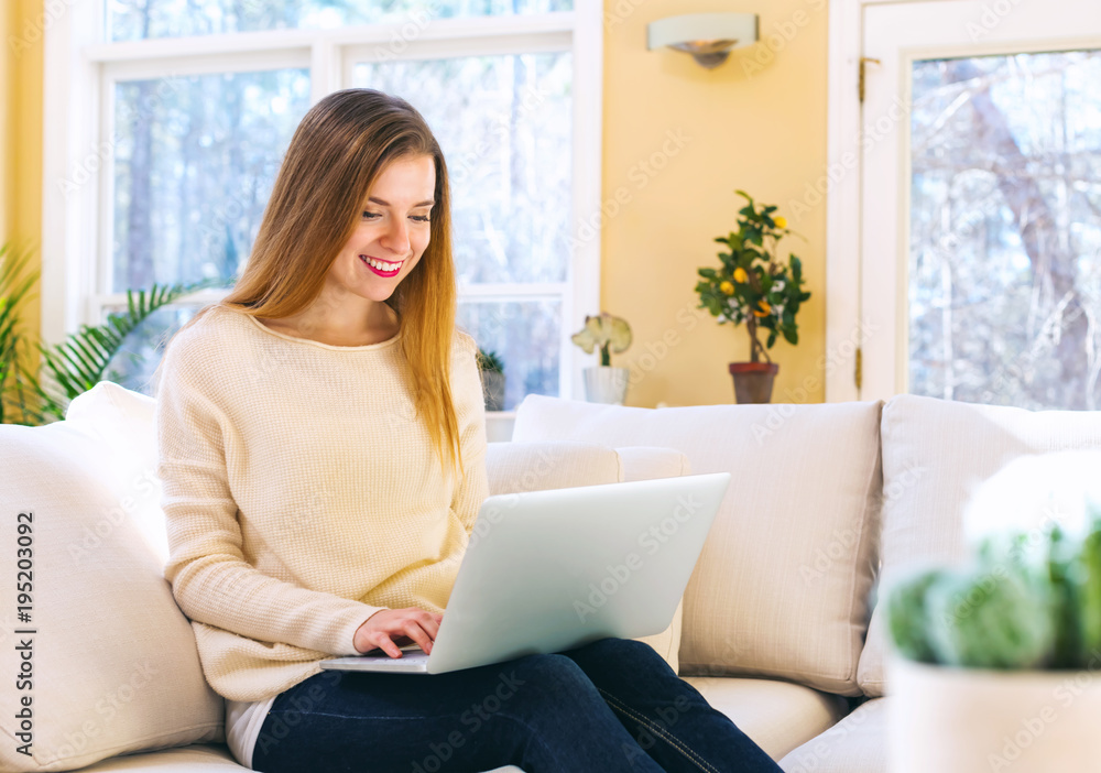 Happy young woman using her laptop computer at home Happy young woman using her laptop computer at home