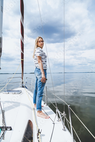 Slender barefoot blonde is standing on white yacht © glebchik