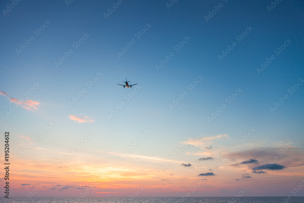 Airplane flying above sea at sunset