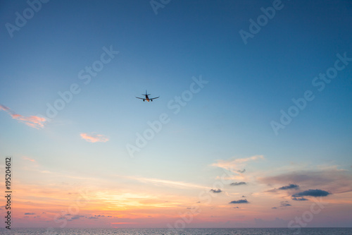 Airplane flying above sea at sunset © takoburito
