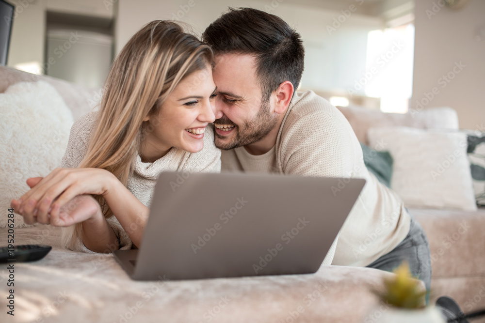 Young couple relaxing on sofa with laptop
