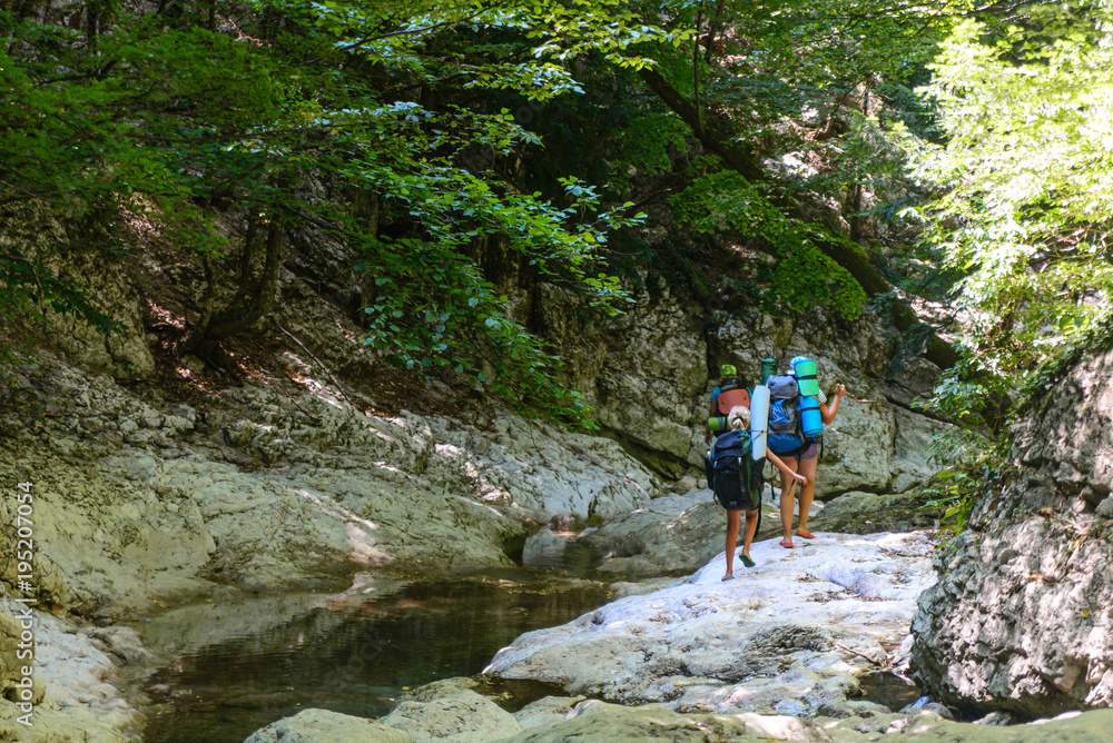 Tourists walk along the rocky bank of a mountain river