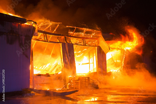 a garage on fire with flames coming thought the roof
