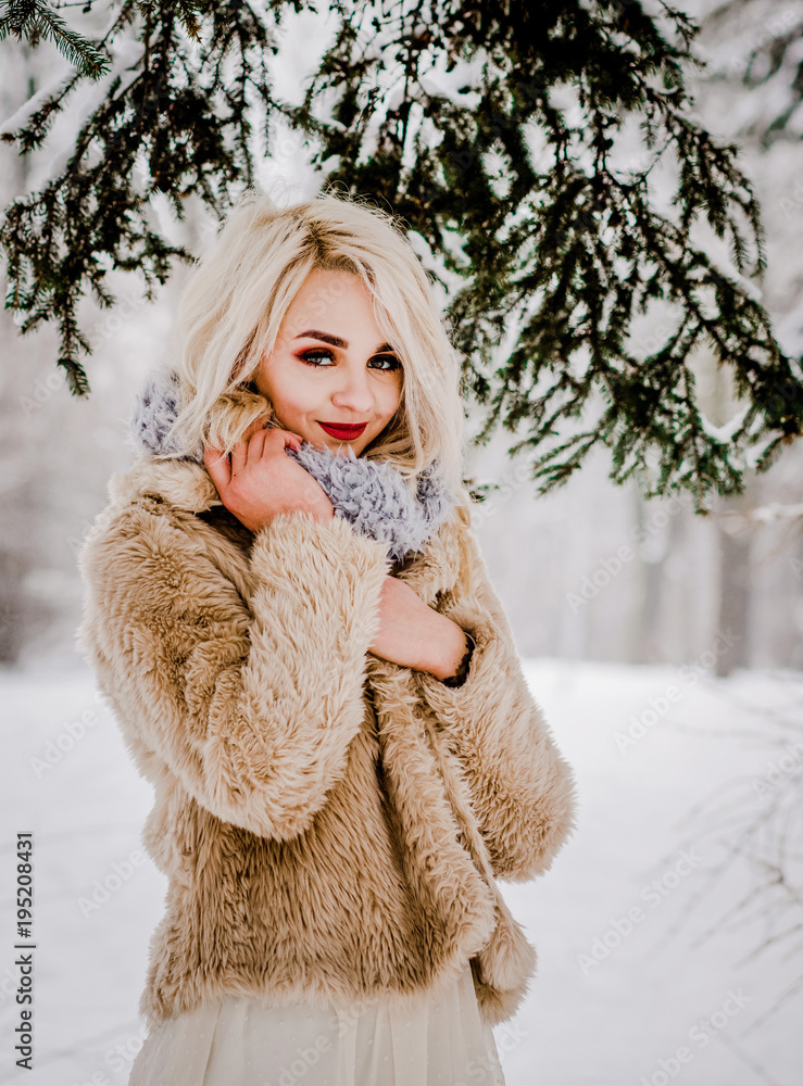 A charming girl standing by the trees in a snowy forest A charming girl standing by the trees in a snowy forest