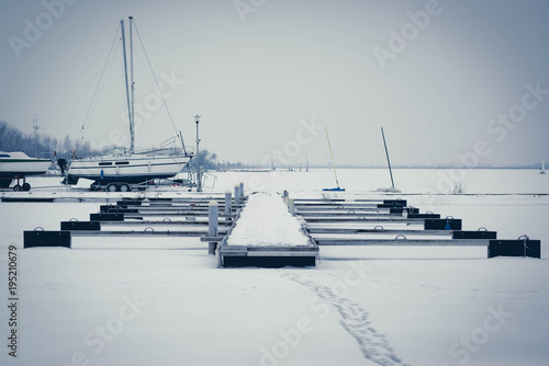 Sailboats moored in foggy harbor. Cold winter landscape with snow and ice