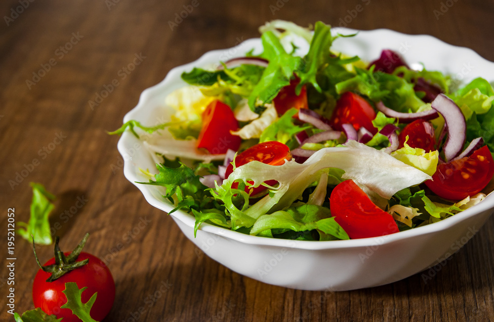 various fresh mix salad leaves with tomato in bowl on wooden background various fresh mix salad leaves with tomato in bowl on wooden background