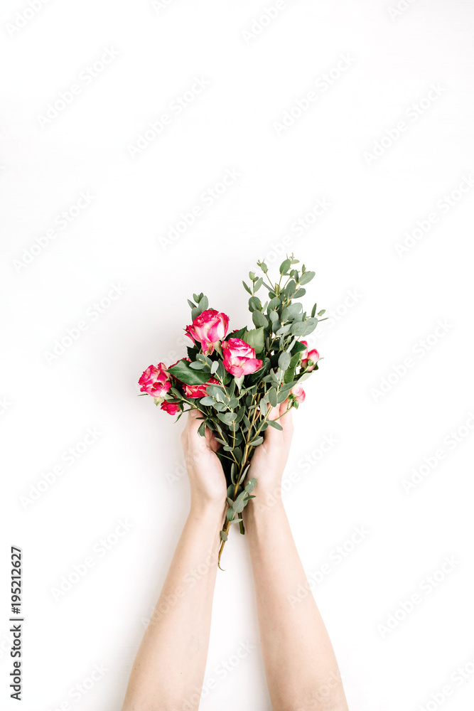 Woman hands hold rose flowers and eucalyptus branch bouquet on white background. Flat lay, top view spring background.