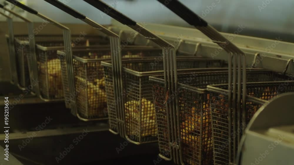 Various baskets of cooked french fries over the fryer Various baskets of cooked french fries over the fryer