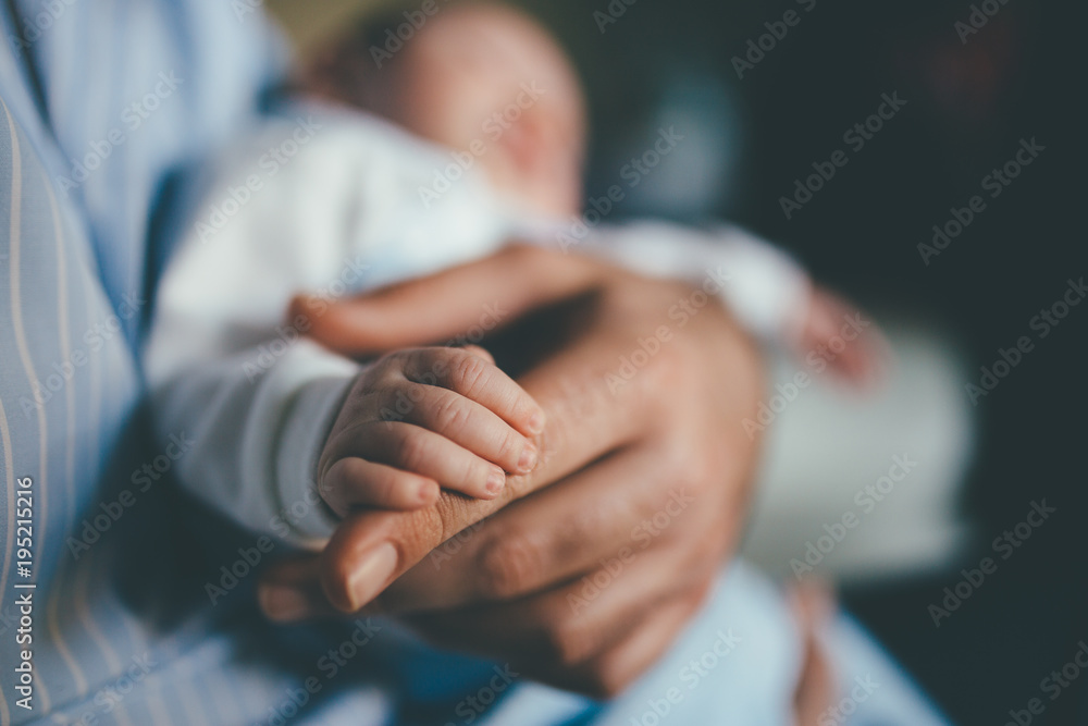 small hand of a newborn supported by the big hand of his father