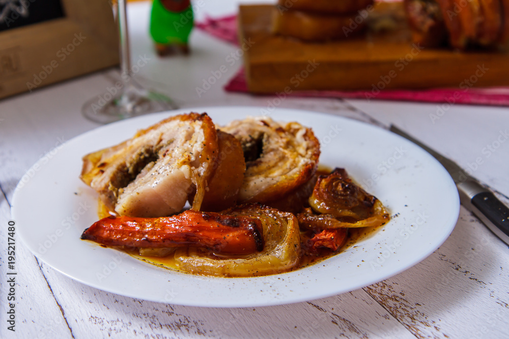 Sliced pork roll with vegetables on a white plate side view. Porketta Sliced pork roll with vegetables on a white plate side view. Porketta