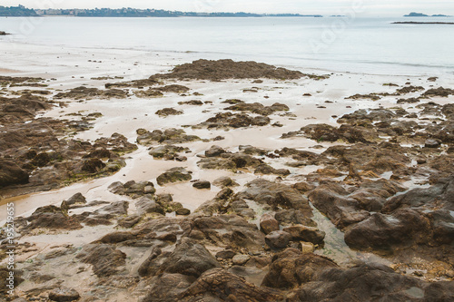 Brown damp stones, rocks and wet sand revealed during low tide on sea shore