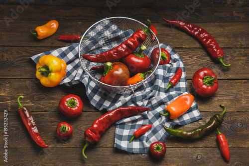 Variety of peppers on a wooden background.