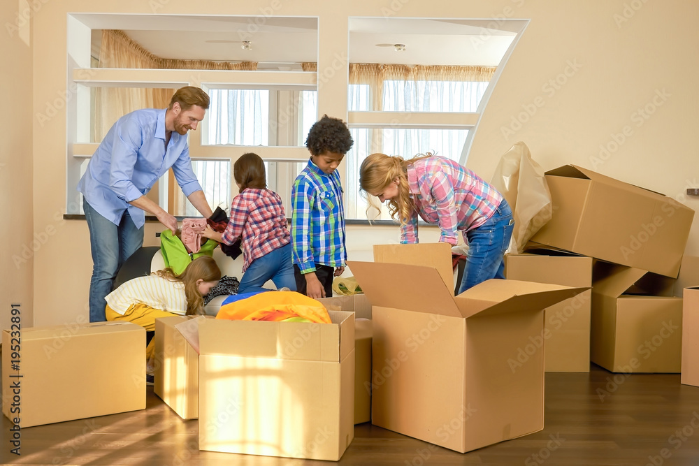 Family is unpacking things. People and cardboard boxes indoor. Family is unpacking things. People and cardboard boxes indoor.
