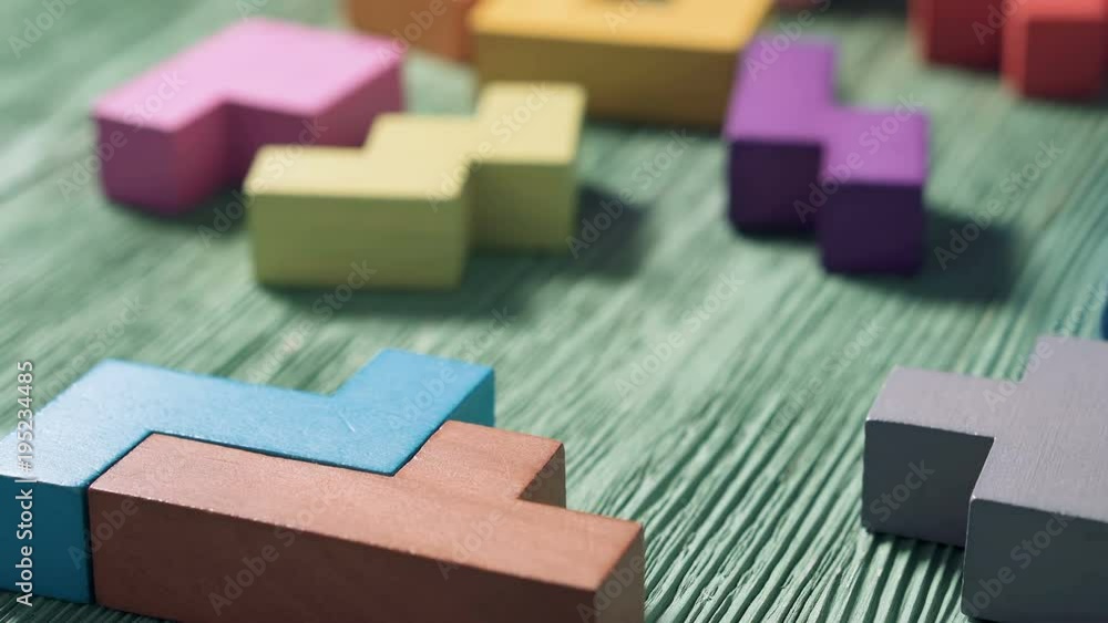 Close up of man's hand folding colorful wooden blocks on the green table background. The concept of logical thinking. Close up of man's hand folding colorful wooden blocks on the green table background. The concept of logical thinking.