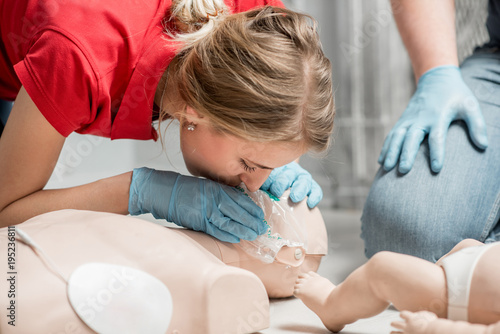 Canvas Print Woman instructor showing how to make artificial respiration with dummy during th