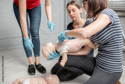 Foto Woman learning how to make chest compressions on a baby dummy during the first a