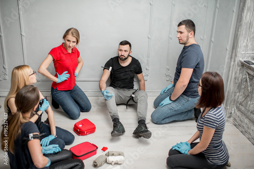 A group of people learning to apply the tourniquet to prevent bleeding during the first aid training indoors