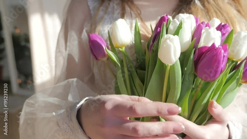 Women's hands are holding a bouquet of tulips