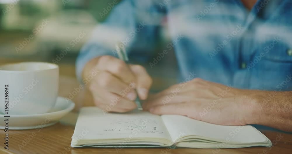 Young man writing in notebook in coffee shop Young man writing in notebook in coffee shop