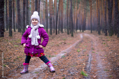 Little cute little girl posing on the road in the autumn forest