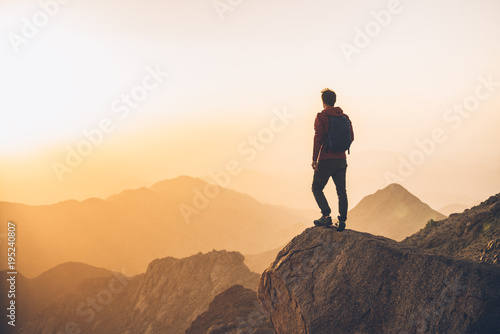 Hiker on a desert mountain summit at sunset photo