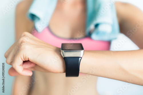 Smartwatch fitness technology concept. Young fit woman using smart watch at the gym.
