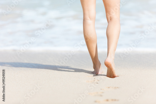 Feet walking on white sand beach. 