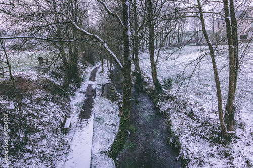 фотографія Rural setting in the village of Carrignavar during Storm Emma, also known as the Beast from the East, which hit Ireland at the start of March: stream surrounded by trees and roads covered in snow
