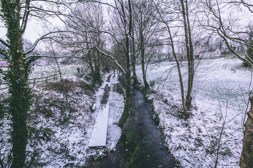 фотографія Rural setting in the village of Carrignavar during Storm Emma, also known as the Beast from the East, which hit Ireland at the start of March: stream surrounded by trees and roads covered in snow
