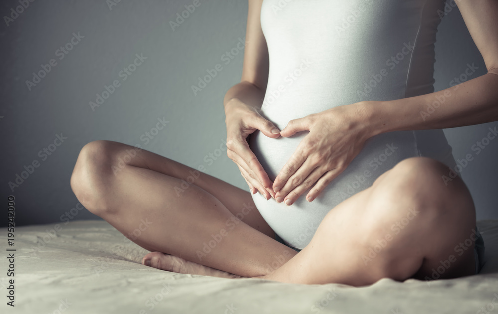 Obraz premium Closeup of pregnant mother making heart on stomach. Pregnancy and expecting a baby concept.