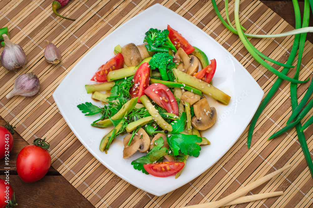 Salad with mushrooms, avocado, tomatoes and greens. Wooden rustic background. Top view Salad with mushrooms, avocado, tomatoes and greens. Wooden rustic background. Top view