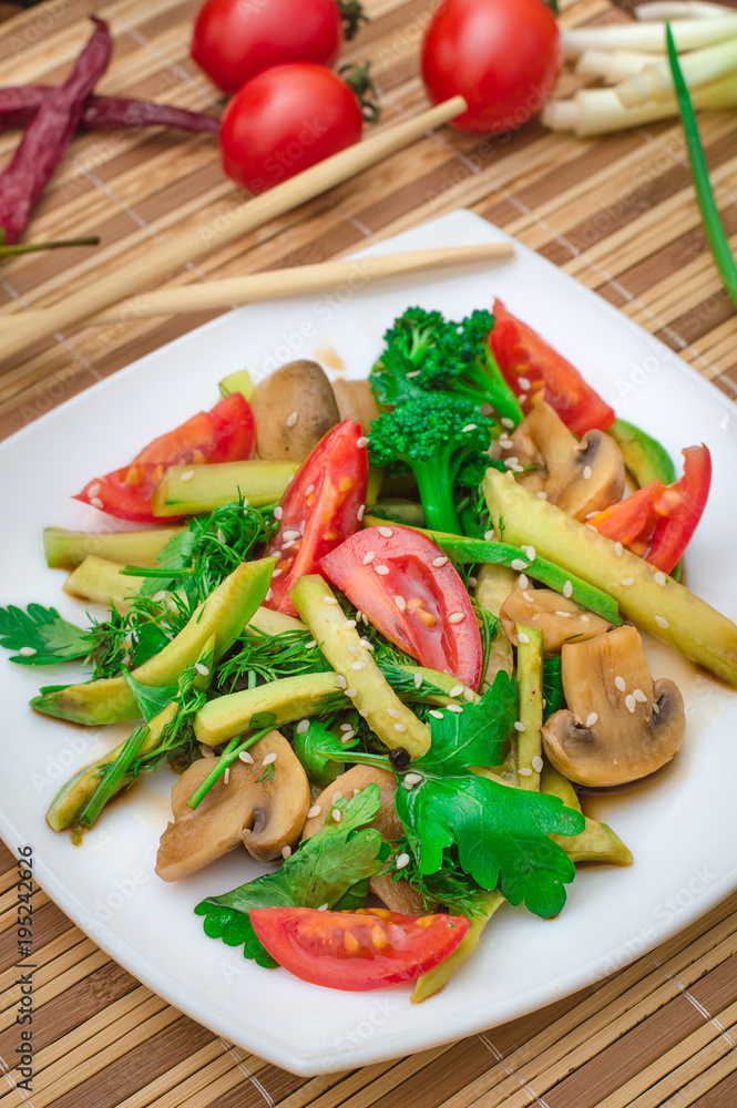 Salad with mushrooms, avocado, tomatoes and greens. Wooden rustic background. Top view