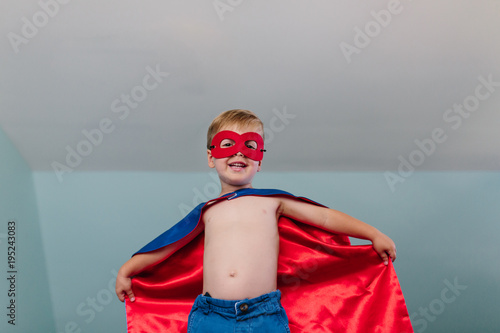 Cute young boy playing superhero at home photo